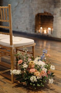 a flower arrangement on the floor next to a chair with a candlelight in the background