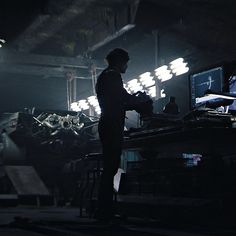 a man standing in front of a computer monitor on a desk next to a keyboard