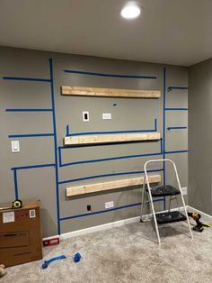 a room that has some shelves and ladders on the wall with blue tape around it