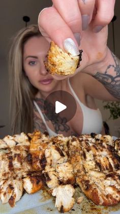 a woman holding up a piece of food in front of her face, with the word chicken on it