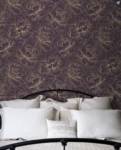 a bed with white pillows and purple wallpaper