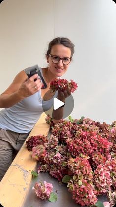 a woman is making pink flowers out of paper