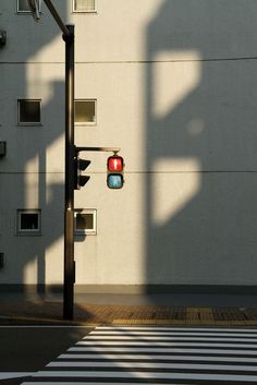 a traffic light sitting on the side of a road next to a tall white building