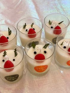 four desserts with strawberries and cream in small glasses on a tableclothed surface