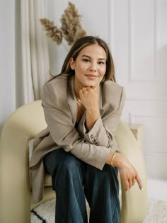 a woman sitting in a chair with her hand on her chin