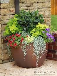 a large potted planter filled with flowers on the side of a brick building