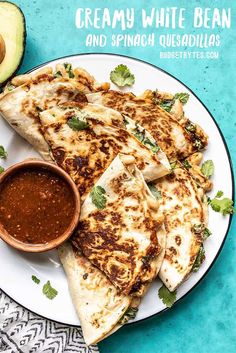 quesadillas on a plate with salsa and avocado next to it