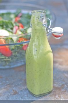 a glass bottle filled with dressing next to a salad