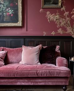 a living room with pink couches and paintings on the wall above them, along with other decor items