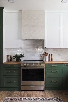 a kitchen with green cabinets and an oven in the center, along with a rug on the floor