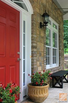 a red front door with two planters on the porch