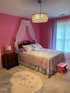 a bedroom decorated in pink and white with a chandelier hanging from the ceiling