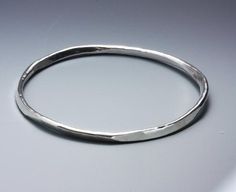 The art of metalsmithing is shown off in this handsome bracelet. It starts as a round piece of wire and is hammered into a six-sided bangle!Since each one is individually made, each one will be unique. This bracelet has a nice, rich, heavy feel to it. Can be custom ordered to your size. Wear one, wear an armful! (I have a customer who does)Size: 8 1/4" inside circumference; 2mm thick.If you are unsure of your size, please convo me for help. Modern Hammered Round Bracelets, Artisan Hammered Bangle Bracelet, Hammered Cuff Bracelet, La Forge, Bracelets Design, The Bangles, London Blue Topaz Ring, Clover Earrings, Hammered Sterling Silver