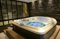 a large hot tub sitting inside of a bathroom next to a wall covered in stone