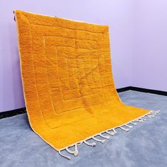 an orange rug is on the floor in front of a purple wall