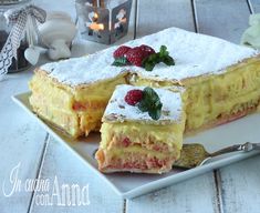 a dessert with raspberries and powdered sugar sits on a plate next to a candle