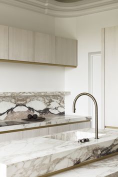 an elegant kitchen with marble counter tops and gold faucet pulls out from the wall