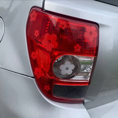 the tail light of a silver car with red flowers on it