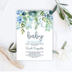 a baby shower is shown with blue flowers and greenery on the bottom, along with an envelope that says'baby in bloom '