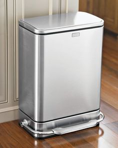 a stainless steel trash can sitting on top of a hard wood floor