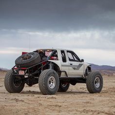 a white truck with four tires on it's flatbed in the desert