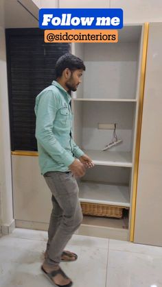 a man standing in front of a bookcase with his foot on the ground next to it