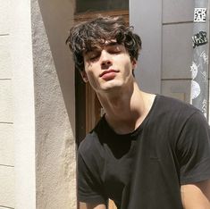 a young man standing in front of a building with his eyes closed and one hand on his hip