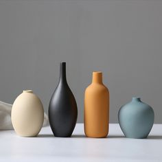 five different colored vases are lined up in a row on a white countertop