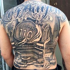 the back of a man's upper half with tattoos on his body and words written in large letters