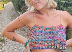 a woman with her hands on her hips wearing a crochet top and shorts