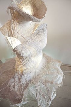 a sculpture made out of plastic sitting on top of a wooden floor next to a white wall