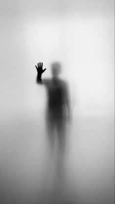 a person standing in the fog with their hand up