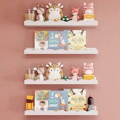 three white shelves with books and toys on them against a pink wall in a children's room