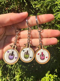 hand holding three small embroidered key chains