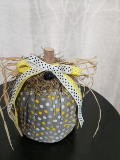 a polka dot pumpkin sitting on top of a black table with yellow and white ribbons