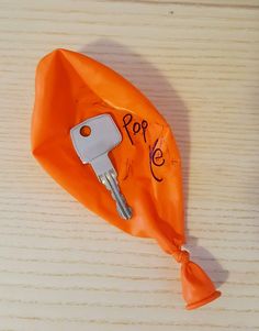 an orange plastic bag with a car key in it and the word pop on it