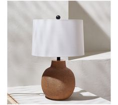 a table lamp sitting on top of a white surface next to a wall and window