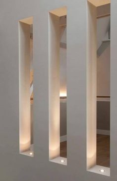 an empty room with three white columns and lights on the wall in front of it