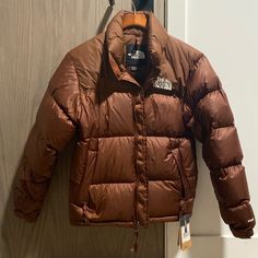 The North Face Men’s 1996 Retro Nuptse Down Jacket In Dark Oak Fit: Relaxed, Hip-Length Silhouette / Interior Hem Shock Cord For Adjustability Warmth: 700-Fill Down Insulation For Premium Loft And Compression Sustainability: 100% Recycled Body, Lining And Overlay Fabrics Durability: Ripstop Fabric With Solid Taffeta Blocking For Abrasion Resistance Details: Attached Three-Piece Hood Packs Into Collar / Secure-Zip Hand Pockets / Jacket Stows In Right Hand Pocket Compatibility: Adjustable Elastic Brown Sport Coat For Winter Outdoor Activities, Brown Down Outerwear For Outdoor, Brown Down Outdoor Outerwear, The North Face Puffer Jacket With Pockets For Outdoor, The North Face Down Outerwear With Pockets, The North Face Puffer Jacket With Pockets For Fall, The North Face Fall Puffer Jacket With Pockets, Casual Brown The North Face Outerwear, Mountain Jacket