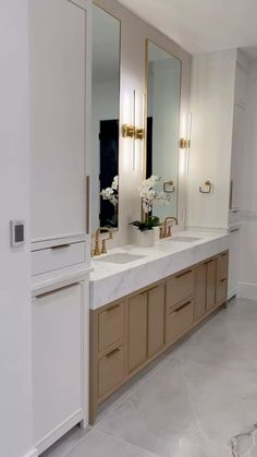 a large bathroom with two sinks and mirrors on the wall next to it's cabinets