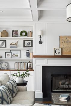 a living room filled with furniture and a fire place in front of a white wall