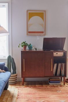 a living room with a blue couch and a laptop on top of a wooden cabinet