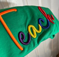 a green t - shirt with the word love embroidered on it