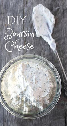 a glass jar filled with sour cream cheese on top of a wooden table next to a spoon