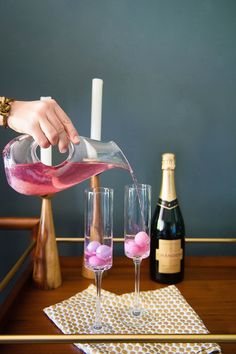 a person pouring pink liquid into wine glasses