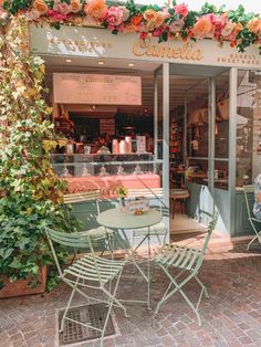 an outdoor cafe with tables, chairs and flowers on the outside wall in front of it