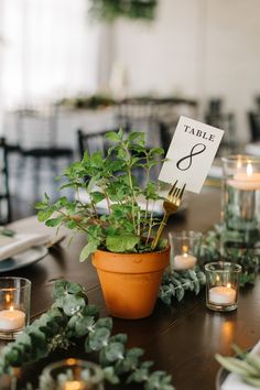 the table is set with greenery and candles