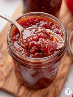 a spoon full of jam sitting on top of a wooden cutting board