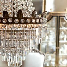 a crystal chandelier hanging from the ceiling in a room with chairs and other furniture