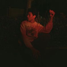 a man sitting on the ground holding a frisbee in his hand at night